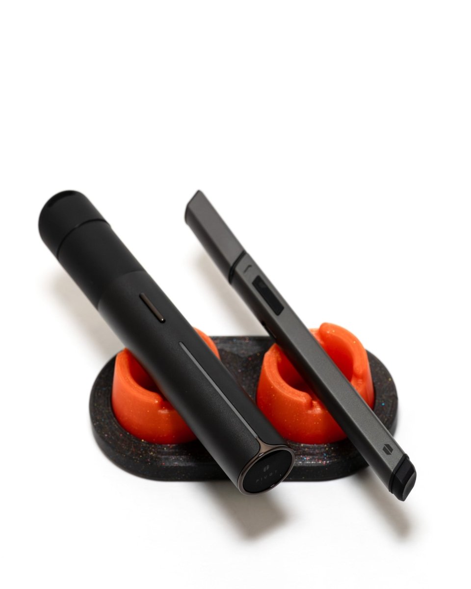 Galaxy Black bubble cap doc with two sunrise orange bubble cap holders show off how a puffco pivot and hot knife fit on their side.